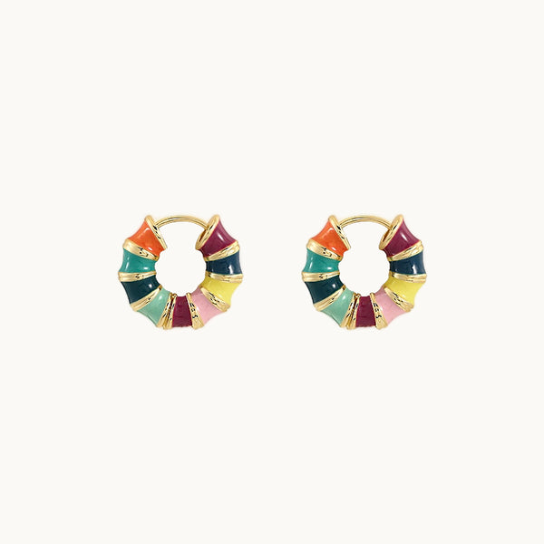 Une paire de boucles d'oreilles est exposée devant un fond beige.  Ce sont des minis créoles dorées multicolores. 