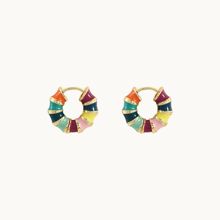 Une paire de boucles d'oreilles est exposée devant un fond beige.  Ce sont des minis créoles dorées multicolores. 