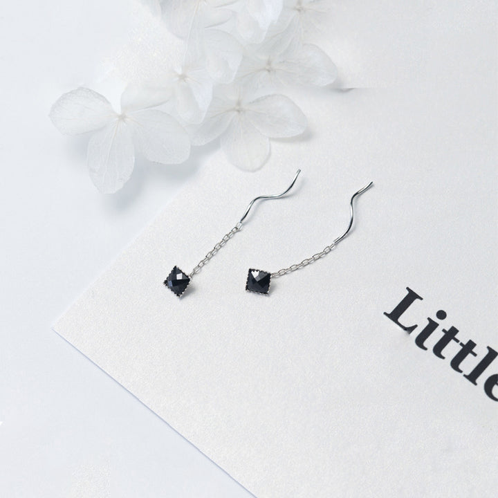 Une paire de boucles d'oreille pendantes en argent 925 avec un pendentif carré noir. Un design élégant et moderne pour les occasions spéciales.