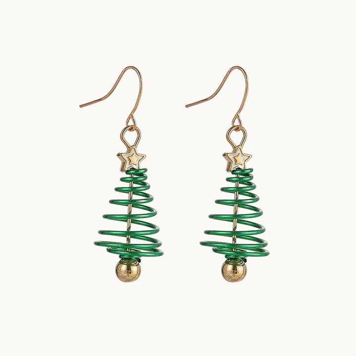 Une paire de boucles d'oreilles est exposée devant un fond beige.  Ce sont des boucles d'oreille pendante. Il y a une étoile dorée sur lequel pend un sapin de noël en forme de spirale verte. Il y a au milieu de la spirale une tige dorée avec une boule dorée au bout. Elles sont dorées et vertes et rappellent noël. 