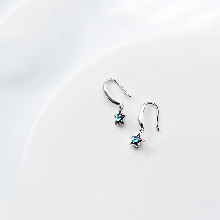 Une paire de boucles d'oreille pendantes en argent 925 avec une étoile en cristal bleu. Un choix élégant et original pour une femme.