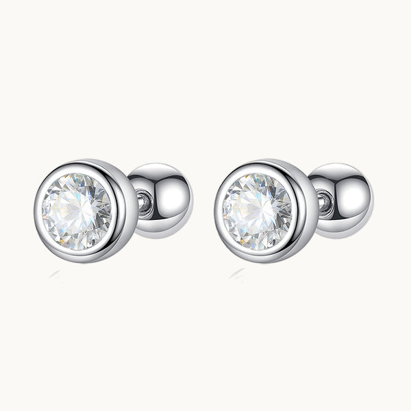 Une paire de boucles d'oreilles est exposée devant un fond beige.  Ce sont des boucles rondes en argent avec un diamant de zirconium. 