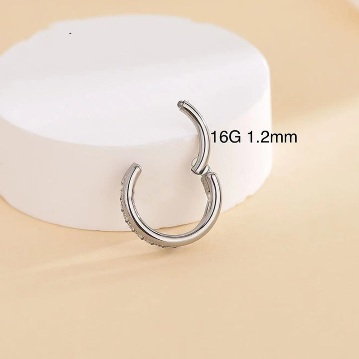 Une boucle d'oreille en titane avec un anneau simple et un demi anneau serti de strass étincelants - Femme.