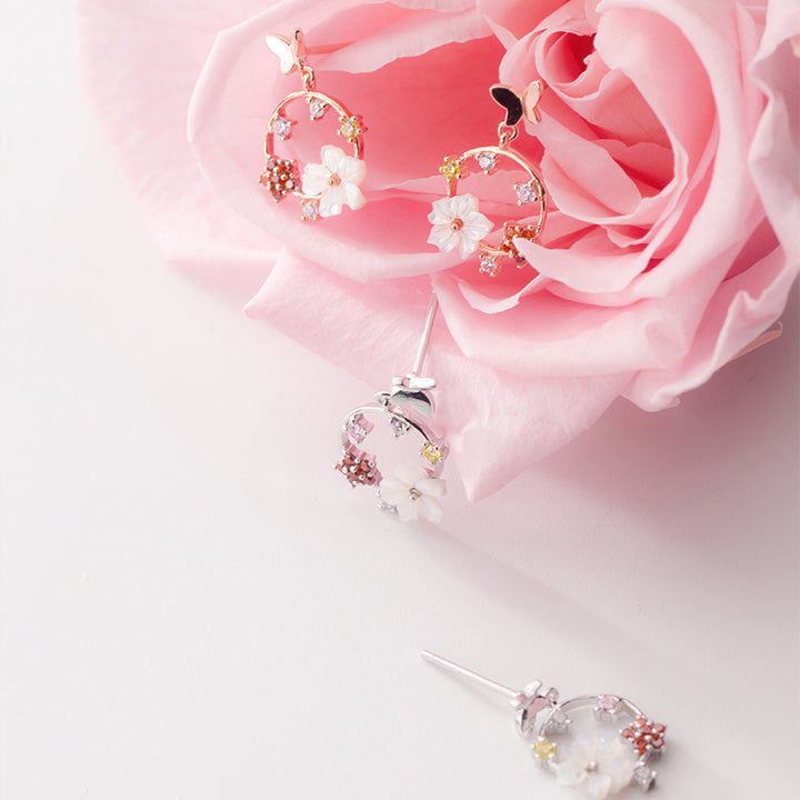 Boucle d'oreille pendante ronde avec papillon et fleurs - Argent 925. Un bijou délicat qui évoque la nature et la féminité.