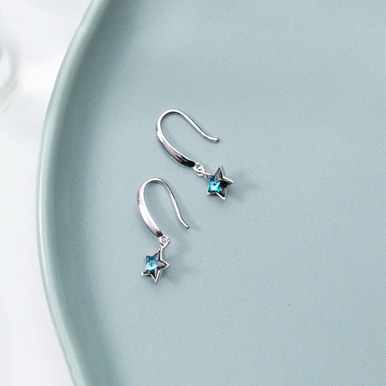 Boucle d'oreille pendante étoile argent 925 avec cristal bleu, ajoutant une touche céleste à votre look féminin.