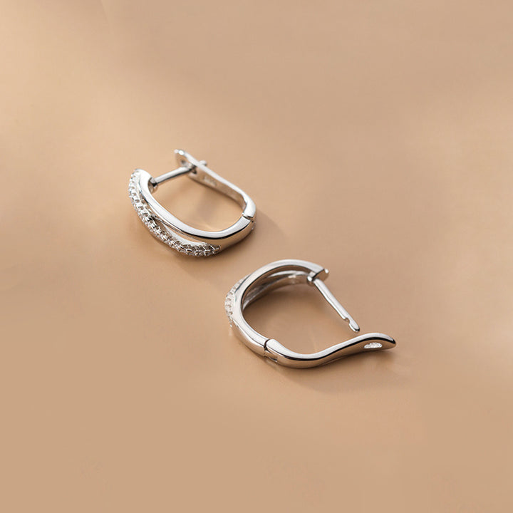 Une paire de boucles d'oreilles dormeuses en argent 925 avec des diamants, croisées avec des anneaux et incrustées de strass scintillants - Femme - Argent 925