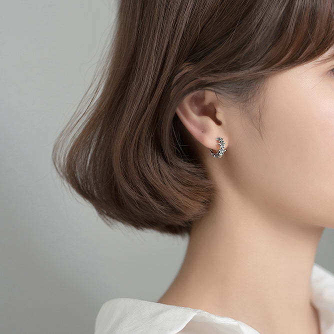 Une femme portant une boucle d'oreille créole en argent vieilli en forme d'étoile - Boucle d'oreille créole étoiles effet vieilli - Femme - Argent 925