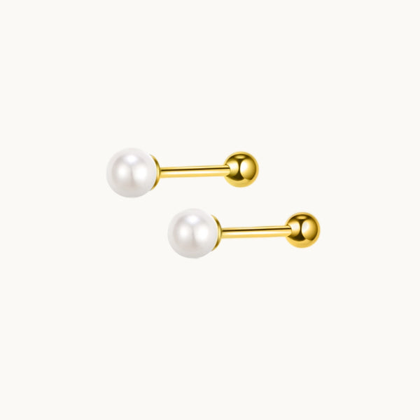 Une paire de boucles d'oreilles est exposée devant un fond beige.  Ce sont des boucles d'oreille avec une tige barre et une perle au bout. Les boucles sont en or. 