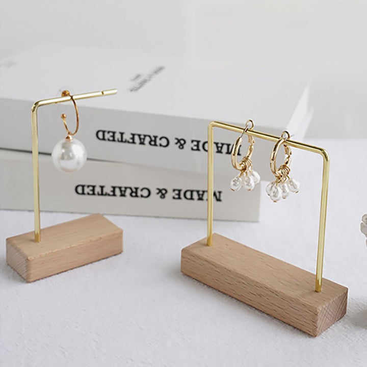 Présentoir support boucles d'oreille en bois et métal doré avec quatre modèles distincts pour mettre en valeur vos bijoux préférés.