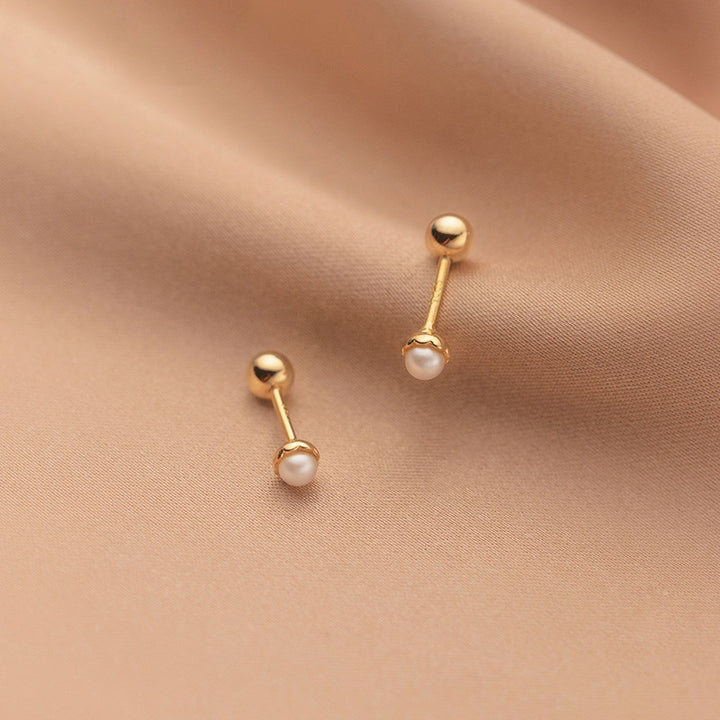 Boucle d'oreille minimaliste en argent 925 avec perle d'eau douce. Fermeture sécurisée en forme de boule métallique. Taille : 0,4 x 0,4 cm. Poids : 0,89 g.