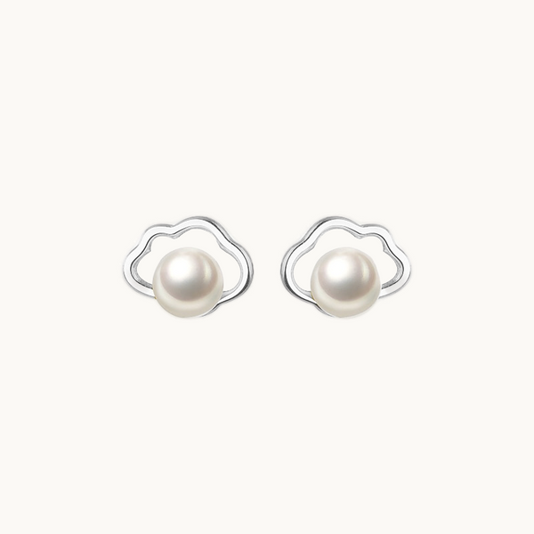 Une paire de boucles d'oreilles est exposée devant un fond beige.  Ce sont des nuages dans lesquels se trouvent une perle. Elles sont en argent 925.
