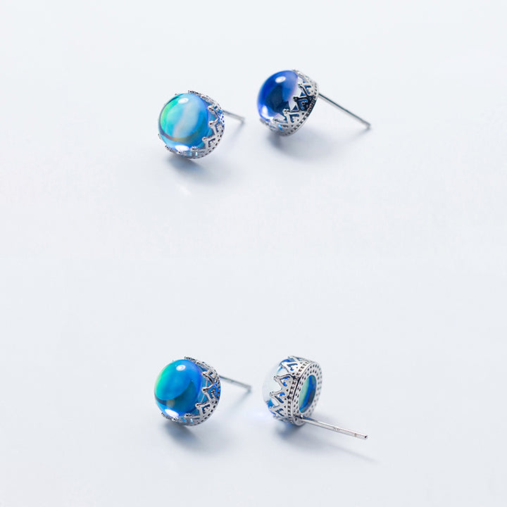 Une paire de boucles d'oreilles en forme de couronne avec un cristal bleu rond, offrant une beauté fascinante. Bijou d'exception en argent 925 pour une allure majestueuse.