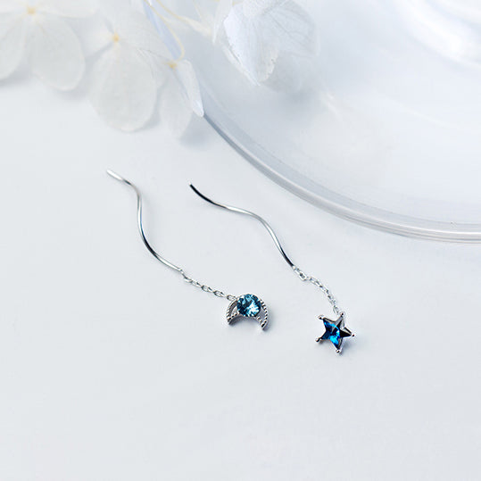 Une paire de boucles d'oreilles pendantes dépareillées en argent 925 avec une étoile bleue et une lune bleue, ornées de diamants de zirconium. Mystère cosmique et élégance pour femme.