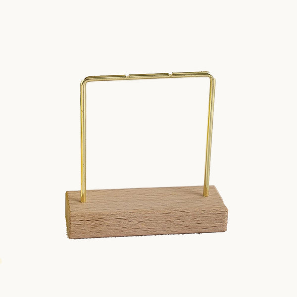 C'est un présentoir pour boucle d'oreille avec un socle rectangulaire en bois et un U inversé en métal doré.