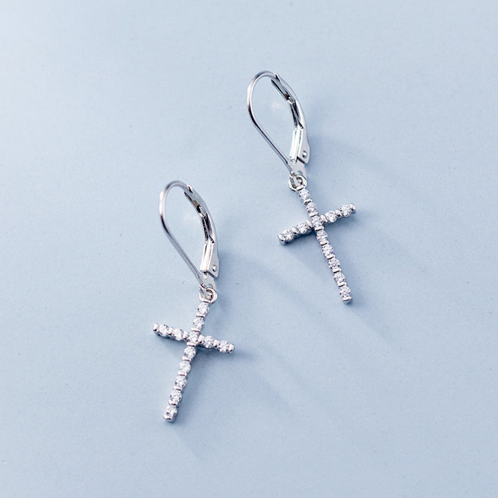 Une paire de boucles d'oreille dormeuses en argent 925 avec une croix pendante ornée de strass scintillants. Un mélange harmonieux de tradition et de modernité pour ajouter une touche de brillance à votre tenue.