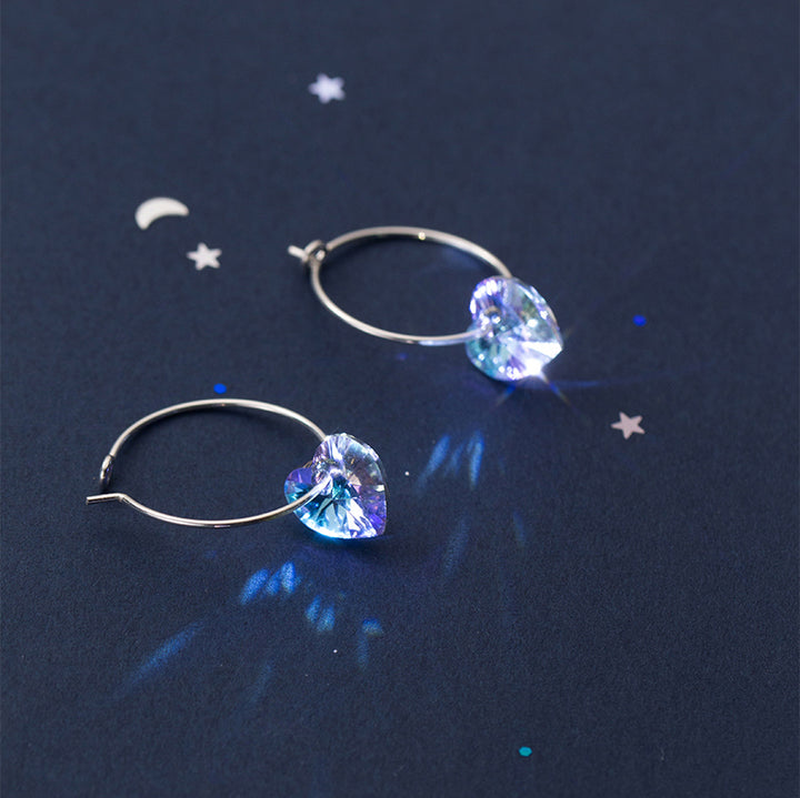 Une paire de boucles d'oreilles créoles fines avec un cœur en cristal suspendu - Femme - Argent 925. Élégance discrète et raffinement inégalé pour sublimer votre allure avec une pointe de féminité mystique.