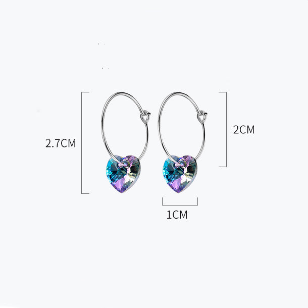 Une paire de boucles d'oreilles créoles fines en argent 925 avec un cœur en cristal suspendu. Un design élégant et féminin qui capture la lumière à chaque mouvement. Une touche de raffinement pour sublimer votre allure.