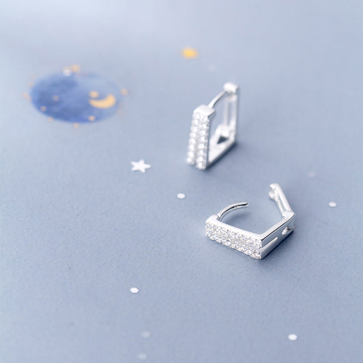 Une paire de boucles d'oreille créoles rectangulaires en argent 925 avec des strass étincelants. Un design audacieux et sophistiqué pour une femme élégante. Poids léger de 2g. Parfait pour ajouter une touche contemporaine à votre look. Disponible sur 1001 Boucles d'Oreille.