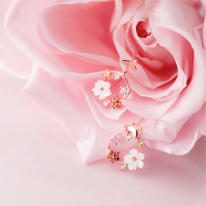 Boucle d'oreille pendante ronde avec papillon et fleurs - Argent 925. Un bijou délicat qui évoque la nature et la féminité.