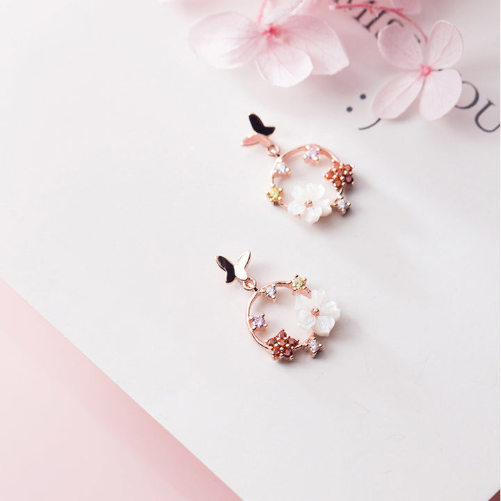 Boucle d'oreille pendante ronde avec papillon et fleurs - Femme - Argent 925. Un bijou délicat évoquant la nature et la féminité.