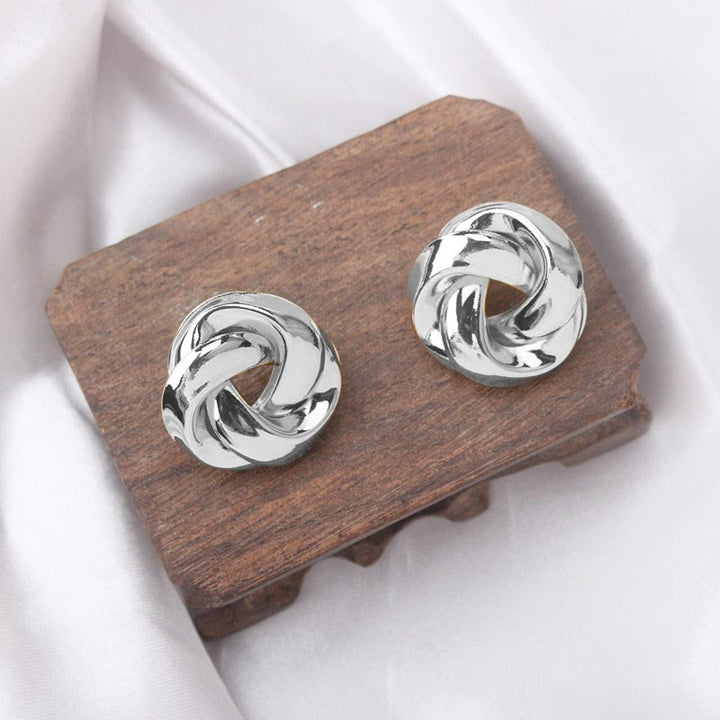 Boucle d'oreille ronde torsadée en argent sur surface en bois - Bijou féminin, élégant et léger pour sublimer chaque jour.