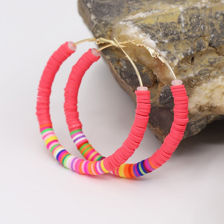 Boucle d'oreille créole avec anneaux plats colorés en argile - Enfant. Un mélange amusant et élégant de fines créoles dorées ornées de multiples petits anneaux plats aux couleurs vives. 12 nuances étincelantes pour égayer la journée de votre petite fille. Dimensions : 65 x 65 mm, poids : 12,5 g.