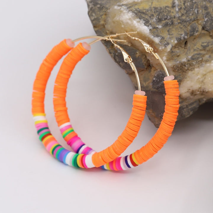 Boucle d'oreille créole anneaux plats colorés argile - Enfant: paire de boucles d'oreille créoles dorées avec multiples anneaux plats en argile aux couleurs vives. Parfait mélange d'amusement et d'élégance pour votre petite fille. Dimensions: 65 x 65 mm. Poids: 12,5 g.