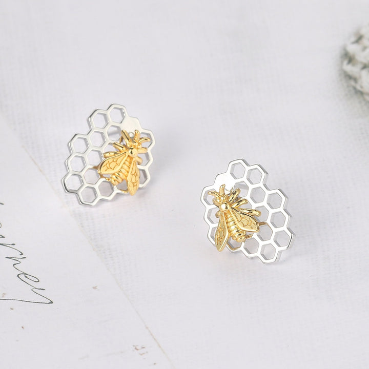 Boucle d'oreille abeille nid d'abeille - Femme: Boucles d'oreille en forme de nid d'abeille avec une abeille, en or et argent, reflétant une élégance naturelle et intemporelle. Matériau : Cuivre. Dimensions : 1,8 x 1,4 cm. Poids : 3,5 g. Style : Boucle d'oreille bicolore.