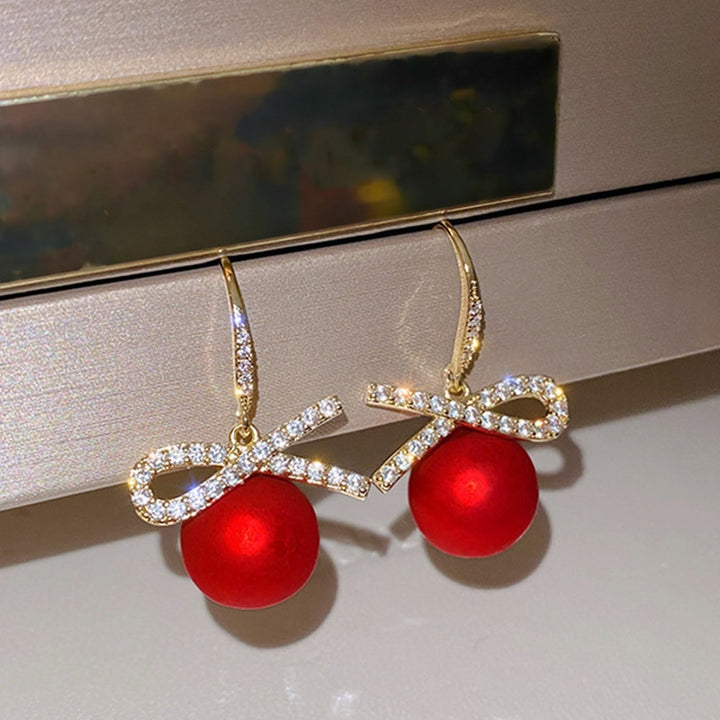 Boucles d'oreille pendantes avec boules rouges et diamants - Femme. Parfaites pour briller lors des fêtes avec leur éclat et originalité.