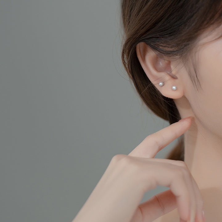 Boucle d'oreille minimaliste avec perle d'eau douce - Femme, Argent 925. Femme avec doigt dans l'oreille.