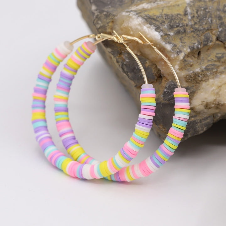 Boucle d'oreille créole anneaux plats colorés argile - Enfant: fines créoles dorées ornées de multiples petits anneaux plats en argile aux couleurs vives. 12 nuances étincelantes pour égayer la journée de votre petite fille. Dimensions: 65 x 65 mm. Poids: 12,5 g.