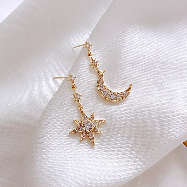 Une paire de boucles d'oreille dépareillées pendantes avec une lune et une étoile en strass et diamants - Femme.