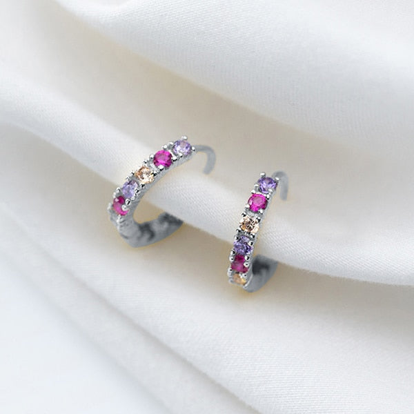 Une paire de boucles d'oreilles créoles en argent 925 avec des strass colorés - Femme - Argent 925. Des pierres roses, violettes et jaunes s'harmonisent pour un éclat multicolore. Dimensions : 1,4 x 0,2 cm.