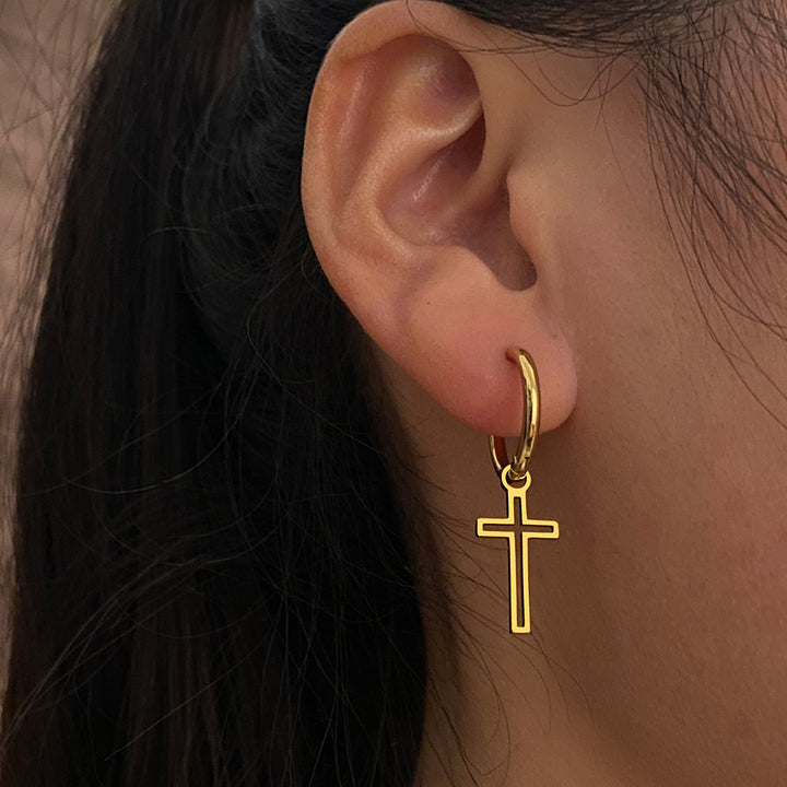 Boucle d'oreille anneau croix ajourée pendante en acier inoxydable pour femme. Détails délicats et élégance intemporelle.