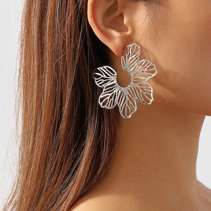 Boucle d'oreille créole fleur ajourée - Femme, une femme portant des boucles d'oreille. Une fleur délicatement ajourée apporte une dimension artistique unique. Idéales pour agrémenter chaque tenue d'une note poétique.