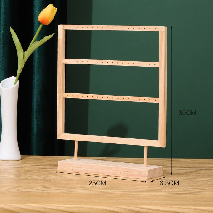 Présentoir en bois rectangulaire avec fleur dans un vase, idéal pour ranger vos boucles d'oreille avec élégance et simplicité. Son design minimaliste s'intègre parfaitement à tout intérieur moderne ou scandinave. Disponible en deux ou trois rangées.