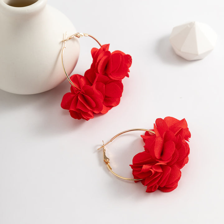 Une paire de boucles d'oreilles créoles dorées avec des fleurs en tissu - Femme. Ajoutez une note délicatement féminine à votre tenue avec ces bijoux élégants et légers. Disponibles en six couleurs séduisantes. Dimensions : 5 x 6,5 cm. Poids : 2,4 g.