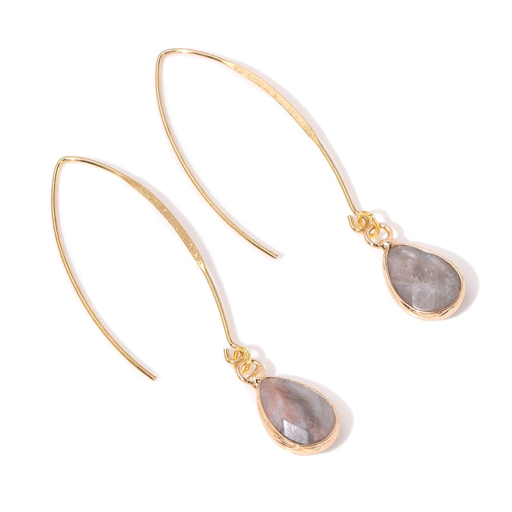 Une paire de boucles d'oreille pendantes en or avec une pierre naturelle en forme de goutte. Un design élégant et moderne pour les femmes soucieuses de leur bien-être.