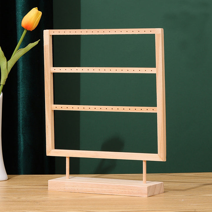 Présentoir en bois rectangulaire avec une fleur dans un vase, idéal pour ranger vos boucles d'oreille avec élégance et simplicité. Son design minimaliste s'intègre parfaitement à tous les décors. Apportez une touche chaleureuse à votre intérieur avec ce présentoir en bois naturel.