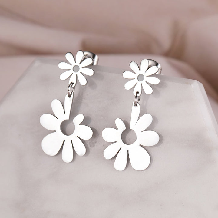 Boucles d'oreille pendantes avec fleurs marguerites, élégantes et poétiques. Pétales réguliers sur la fleur supérieure, contrastant harmonieusement avec la fleur pendante aux pétales variés. Acier inoxydable plaqué or ou argent, ajoutant une touche florale raffinée à votre allure.