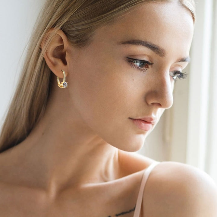 Une femme regarde par la fenêtre, portant des boucles d'oreille dormeuse diamant strass en argent 925. Parfaites pour toutes les occasions.