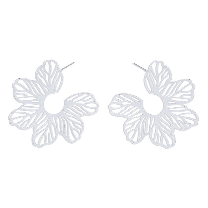 Boucle d'oreille créole fleur ajourée - Femme, une paire de boucles d'oreille en métal blanc avec une délicate fleur ajourée, idéale pour ajouter une touche artistique à chaque tenue. Disponible en finitions dorée ou argentée. Dimensions : 5,9 x 5,7 cm. Poids : 16,6 g.