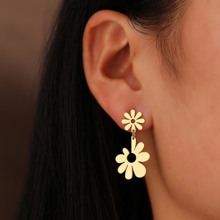 Boucle d'oreille pendante avec double fleur marguerite en acier inoxydable plaqué or ou argent. Ajoute une touche florale raffinée à votre allure.