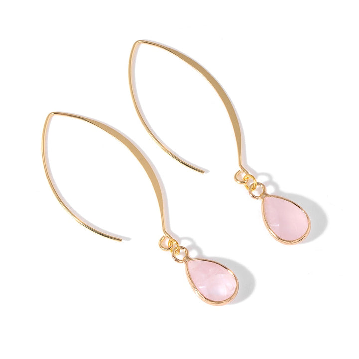 Une paire de boucles d'oreille pendantes en or avec une pierre naturelle en forme de goutte. Design ovale non fermé pour une sophistication moderne. Ajoutez une touche d'authenticité et de mystère à votre look avec ces boucles d'oreille élégantes.