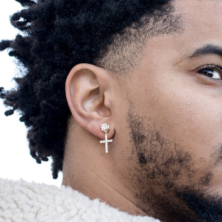 Un homme portant une boucle d'oreille en croix avec un diamant et des strass scintillants. Un style hip-hop audacieux pour un look sophistiqué et audacieux.