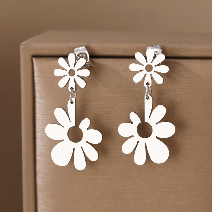 Boucles d'oreille pendantes avec double fleur marguerite en acier inoxydable plaqué or ou argent. Ajoutez une touche florale raffinée à votre allure féminine.