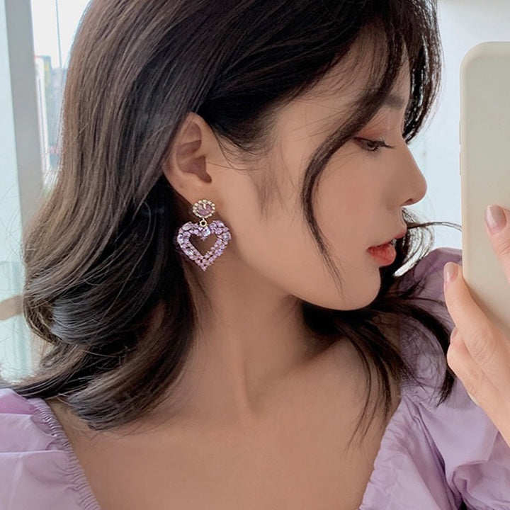 Une femme prenant un selfie avec des boucles d'oreilles en forme de cœur et des strass étincelants - Femme.