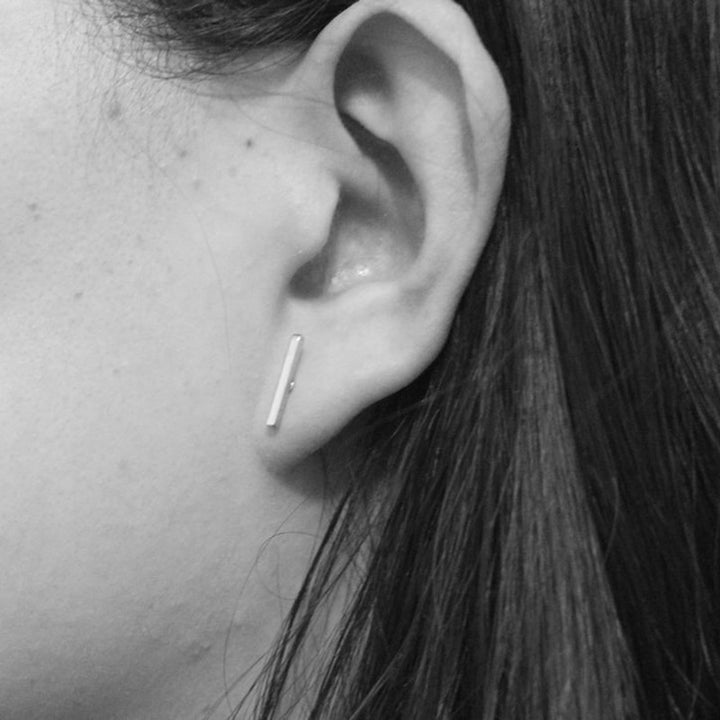 Boucle d'oreille rectangulaire fine minimaliste - Femme: une vue rapprochée de l'oreille d'une femme avec des boucles d'oreille. Un design élégant et discret pour compléter une tenue chic.
