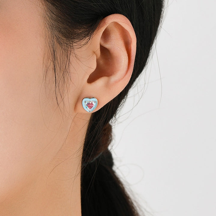 Boucle d'oreille coeur bleu diamant bleu rose - Femme - Argent 925. Une vue rapprochée de l'oreille d'une femme avec une boucle d'oreille en forme de coeur et un diamant de zirconium aux reflets magnifiques.