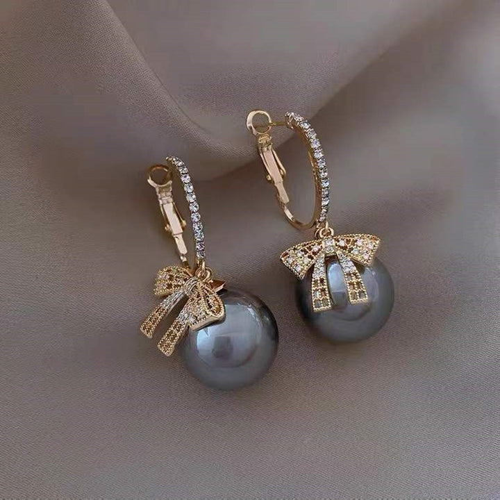 Une paire de boucles d'oreille dormeuses avec un nœud et des diamants. Parfaites pour illuminer votre look festif pendant la période de Noël.